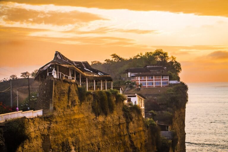 Couple walking on Olón beach at sunset with the cliff-top sanctuary behind