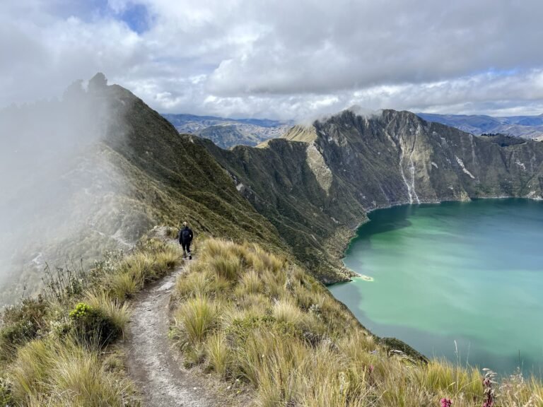 Hiker on the rim of Quilotoa crater above the turquoise lake