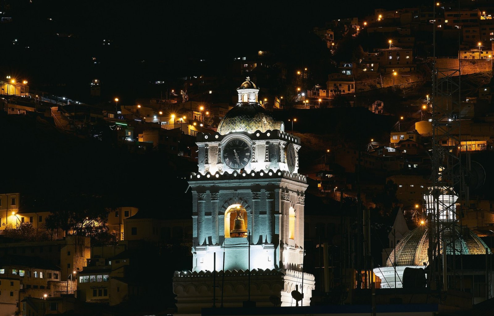 Quito's old town at night: the lit clock tower of Santo Domingo church below a hillside of lights
